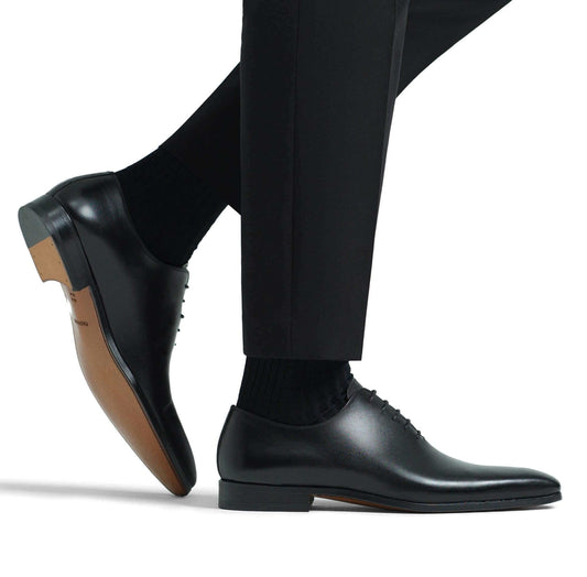 stringate marrone eleganti indossate da uomo con pantaloni eleganti, visualizzate di lato su sfondo bianco.