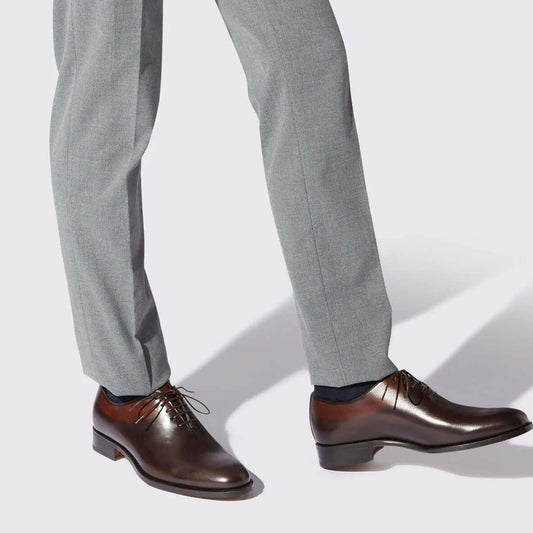 Outlet marchi lusso Made in Italy: eleganti scarpe in pelle indossate con pantaloni grigi.