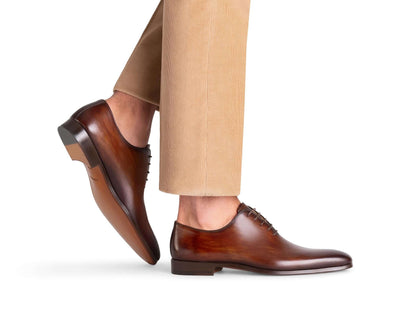stringate marrone eleganti modello a taglio intero in pelle lucida, indossate con pantaloni beige.