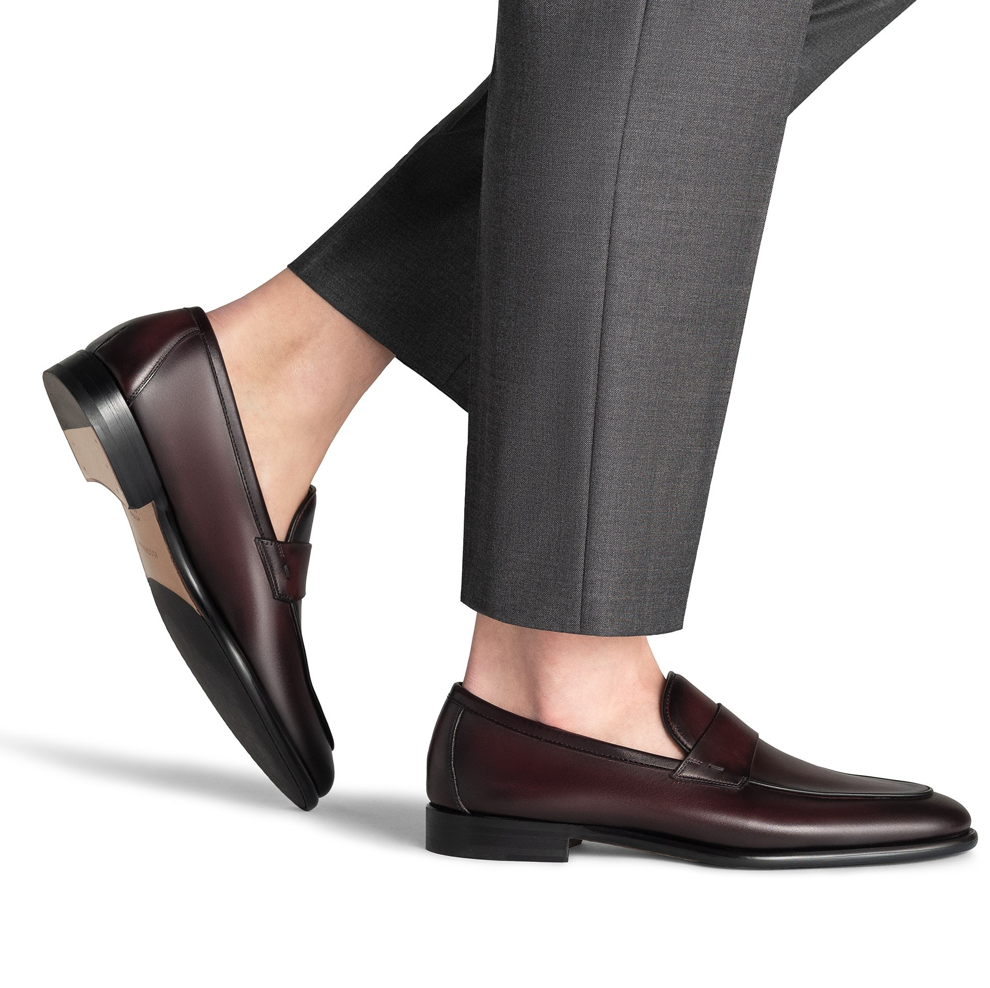 Mocassini eleganti in pelle indossati da uomo con pantaloni grigi, mostrando un design sofisticato e di alta qualità.